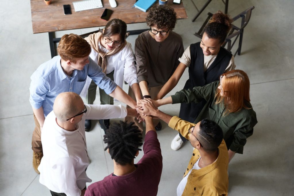 Team of people in a circle placing hands together.