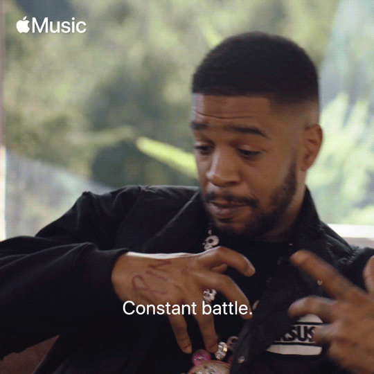 Kid Cudi moving his body and raised hands left and right saying "Constant battle."