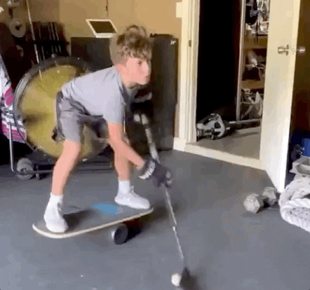 Kid practising hockey on a skateboard.