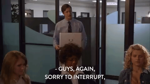 Man entering meeting room carrying a laptop saying "Guys, again sorry to interrupt."