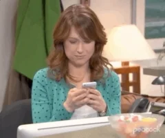 A woman staring at her phone and laughing. 