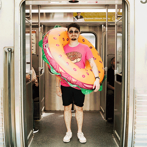 Man wearing bagel sandwich pool floaty standing into front opening and closing subway door.