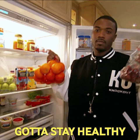 Popular singer and television personality Ray J is holding a bag of oranges and grapes in front of an open refrigerator. He is saying "Gotta Stay Healthy".