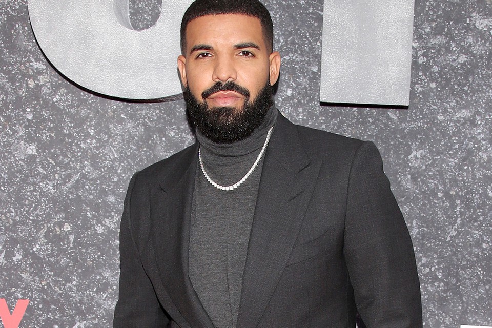 Canadian rapper Drake is dressed in a grey suit and chain.