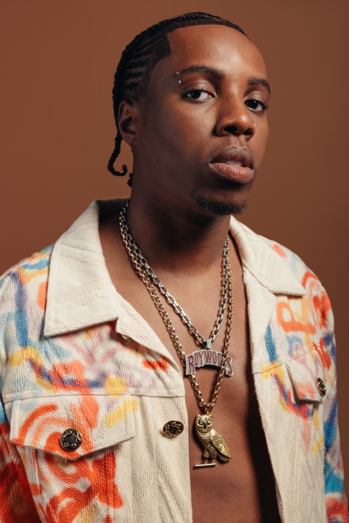 Roy Woods is dressed in a multi-coloured denim jacket.