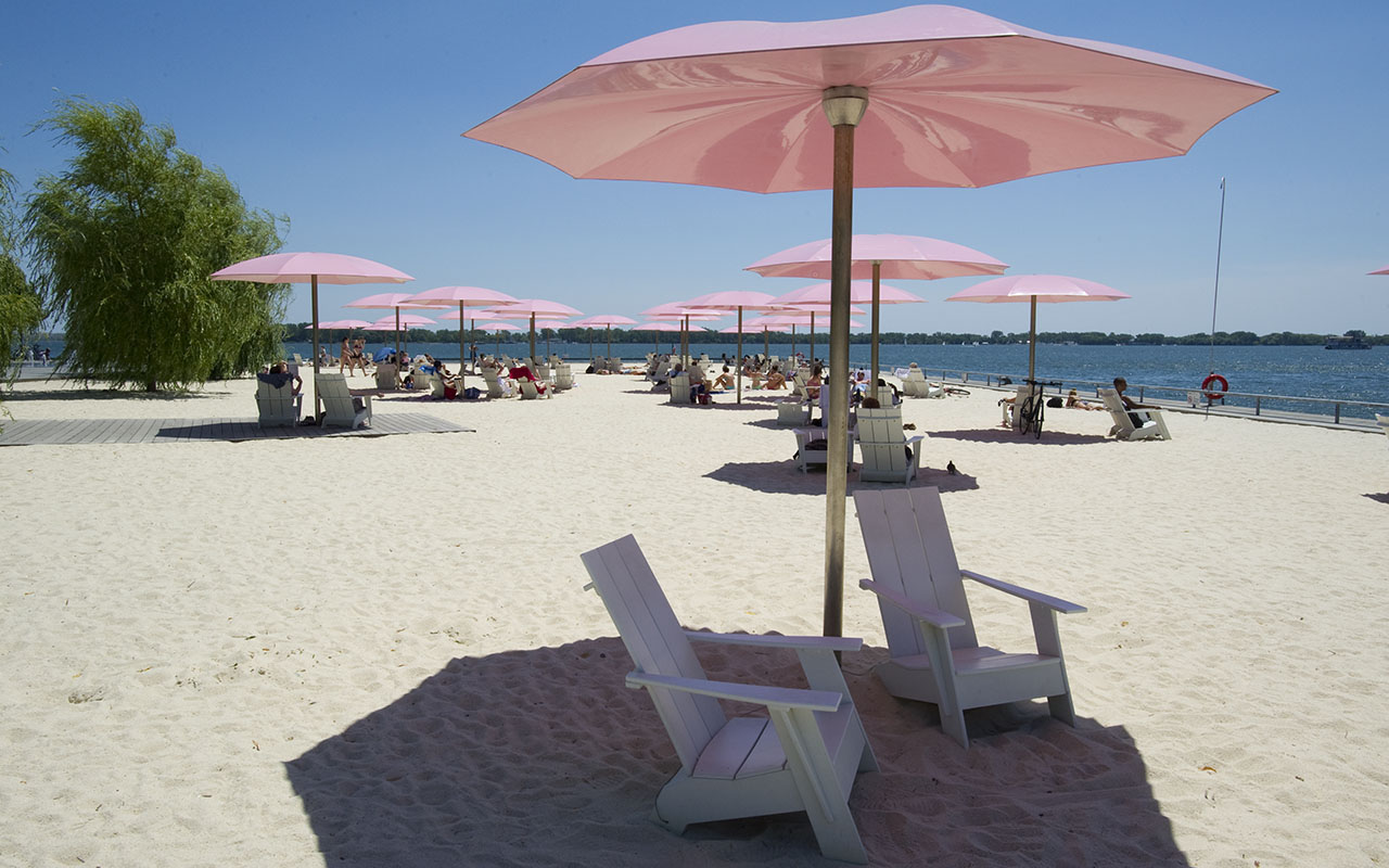 White chairs and pink umbrellas at the beach.