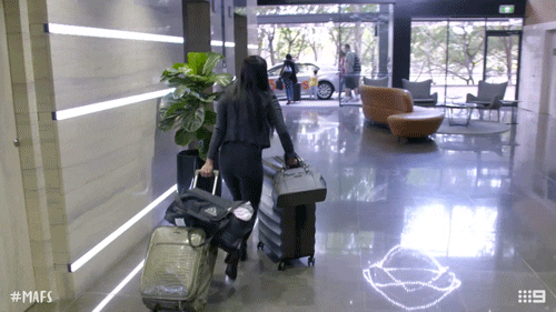 A lady is walking through a hotel lobby with a lot of luggage. (backpack essentials)