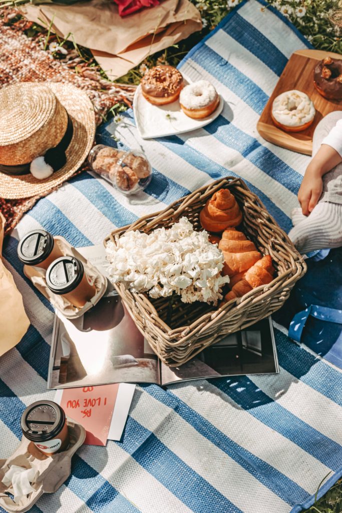Picnic blanket with a basket filled with food and coffee. 
