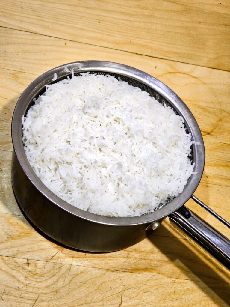 Cooked rice resting in a stainer