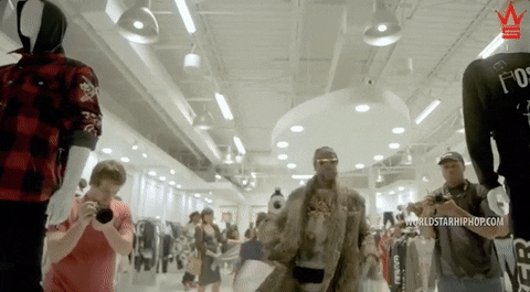 2Chainz is leaving a store with many bags.
