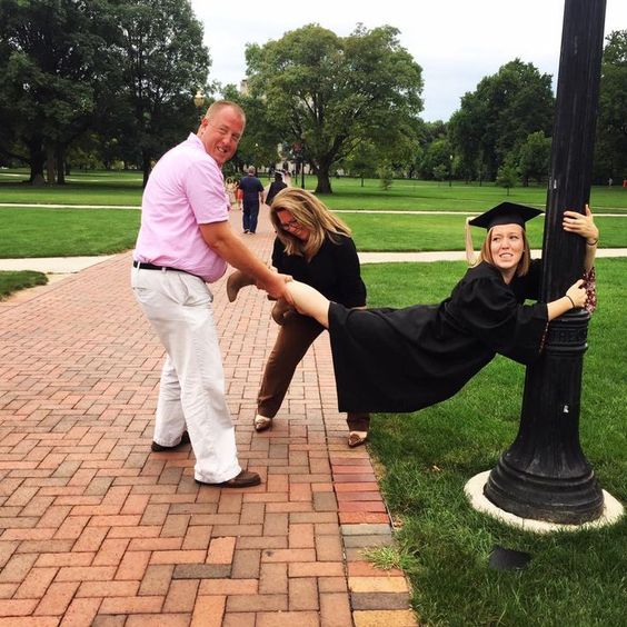 A college graduate is taking photos with her parents. She is hanging onto a poll with help from her parents. (Internet)