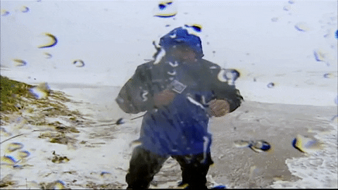A weatherman remarks "We are just getting hammered!" while reporting in gusting wind and rain.