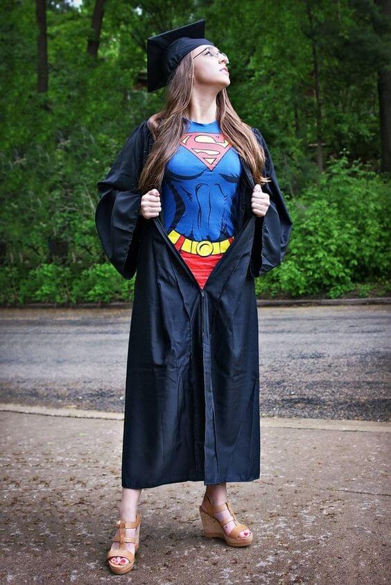 A graduate is wearing a Superman outfit underneath her graduation gown.