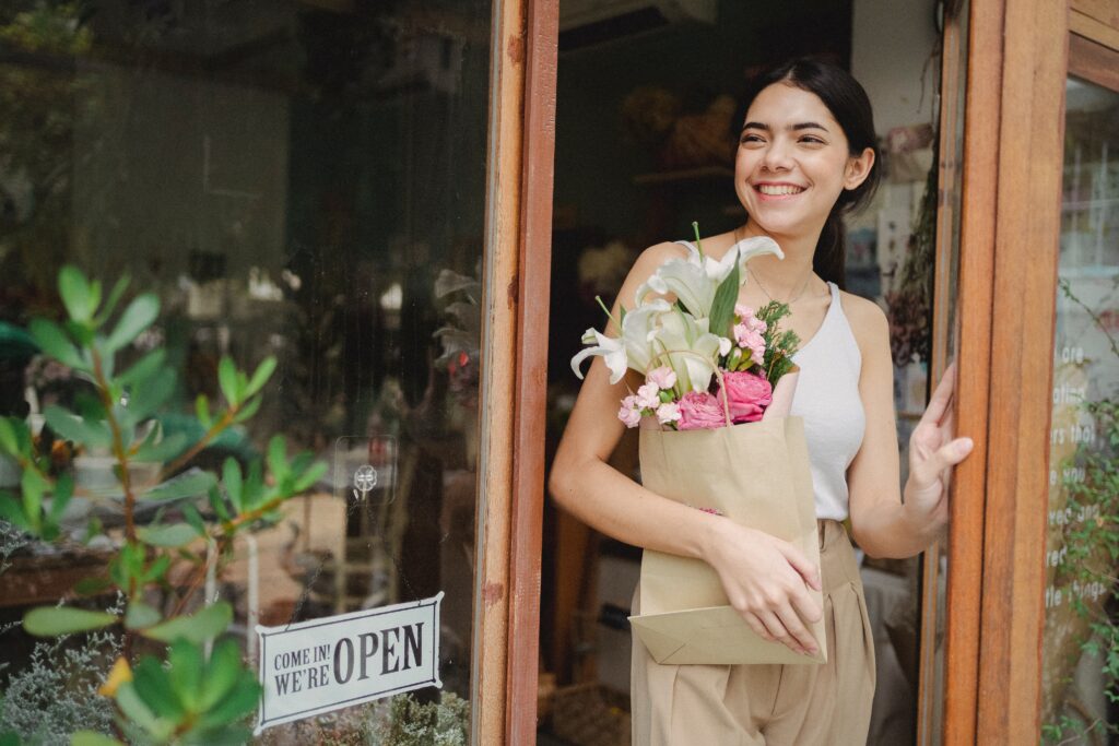 Woman holding a bag of flowers and smiling.