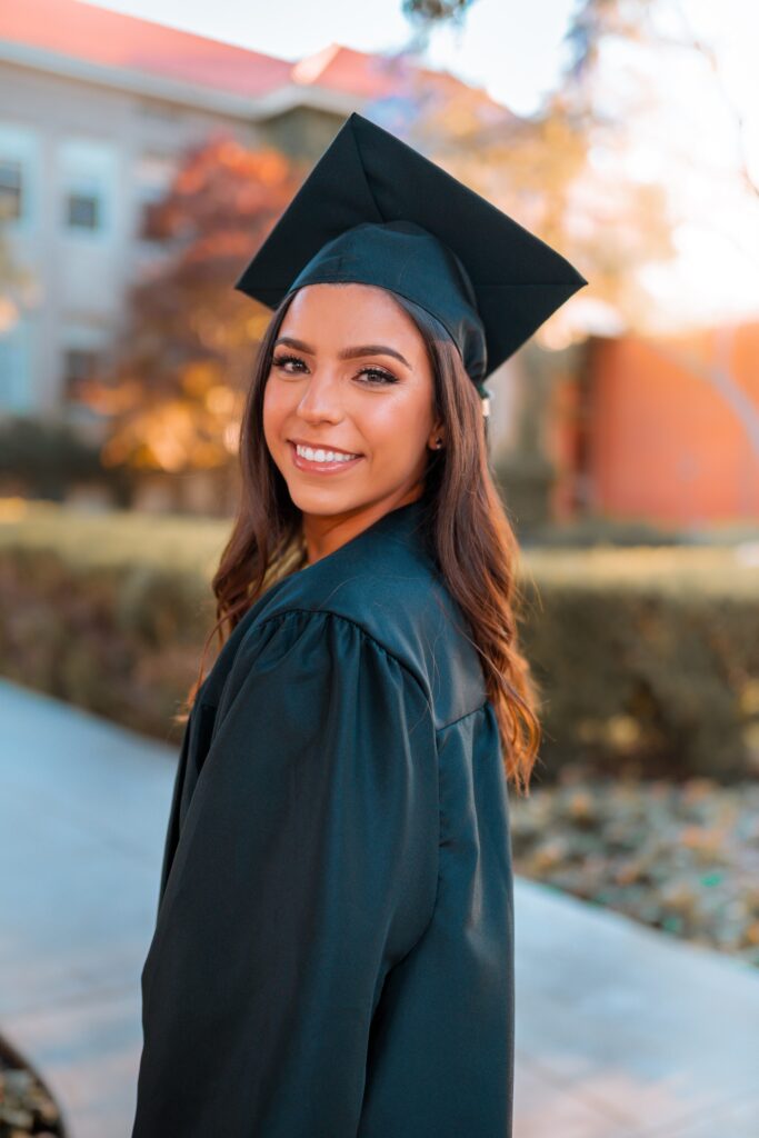 A graduate is smiling and posing for her grad photos.  (Internet)