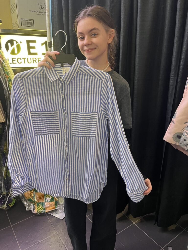 Dzhuliia, IGNITE's employee is holding one of long sleeve shirts on sale.