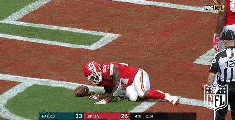 An NFL player taking a nap on a field.