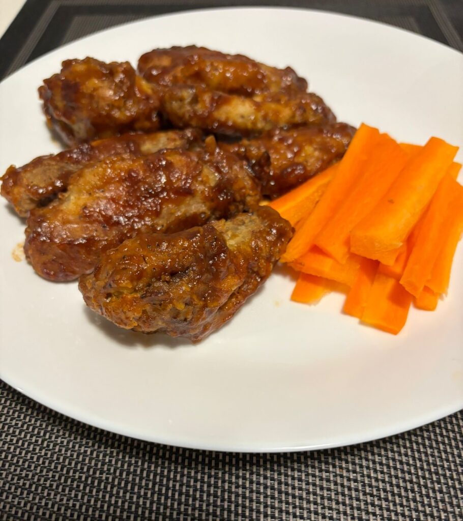 A serving of Chinese chicken wings and carrot stick served with creamy dill sauce.