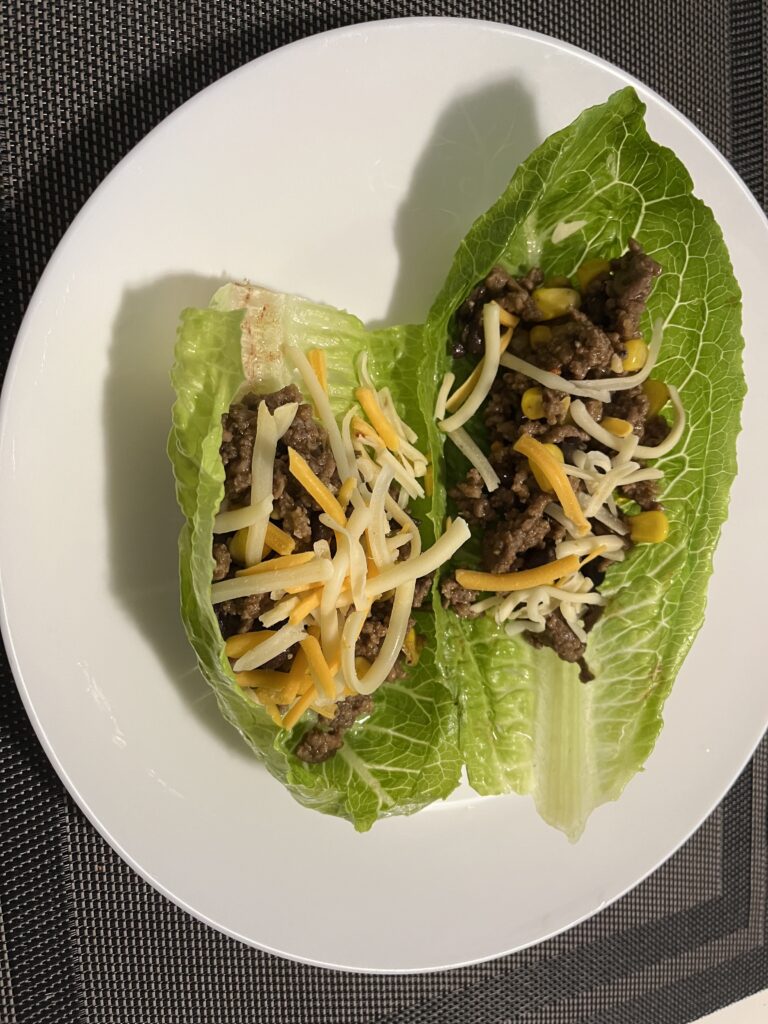 A serving of lettuce wraps made with ground turkey, black beans, sweet corn with cheese sprinkled on top.