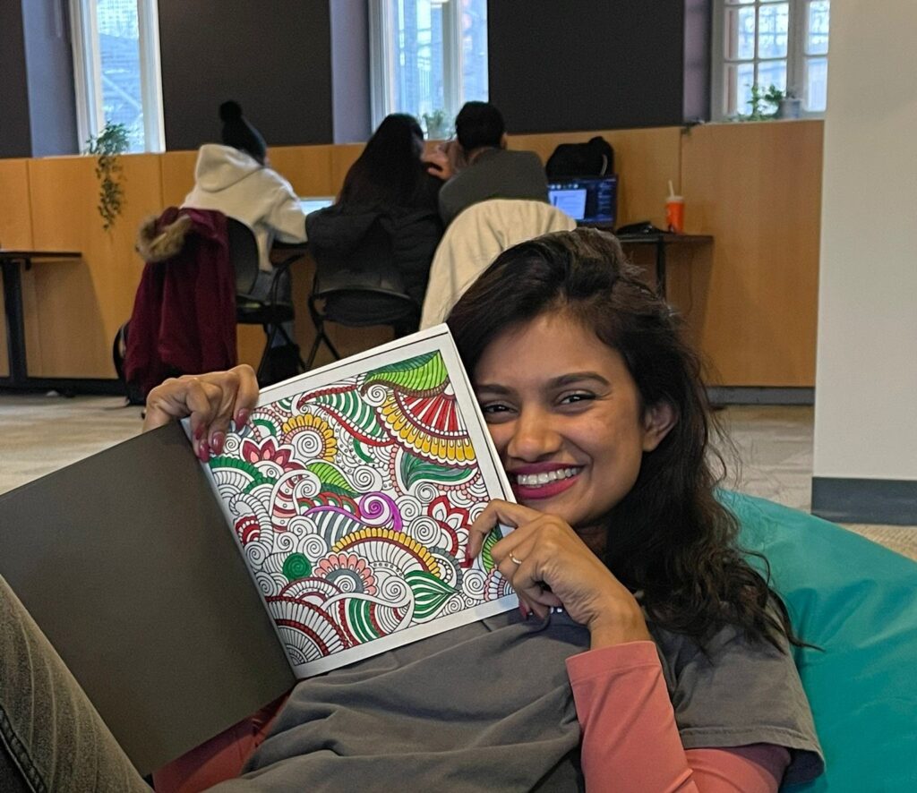 A woman holding out a colouring book smiling.