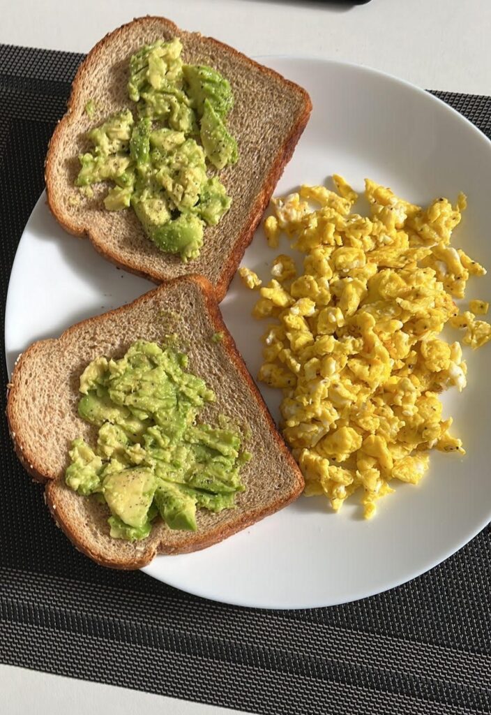 A plate of scrambled eggs and avocado toast.