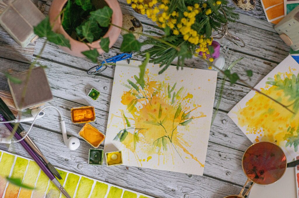 A painting in yellow and green with nature prints.
