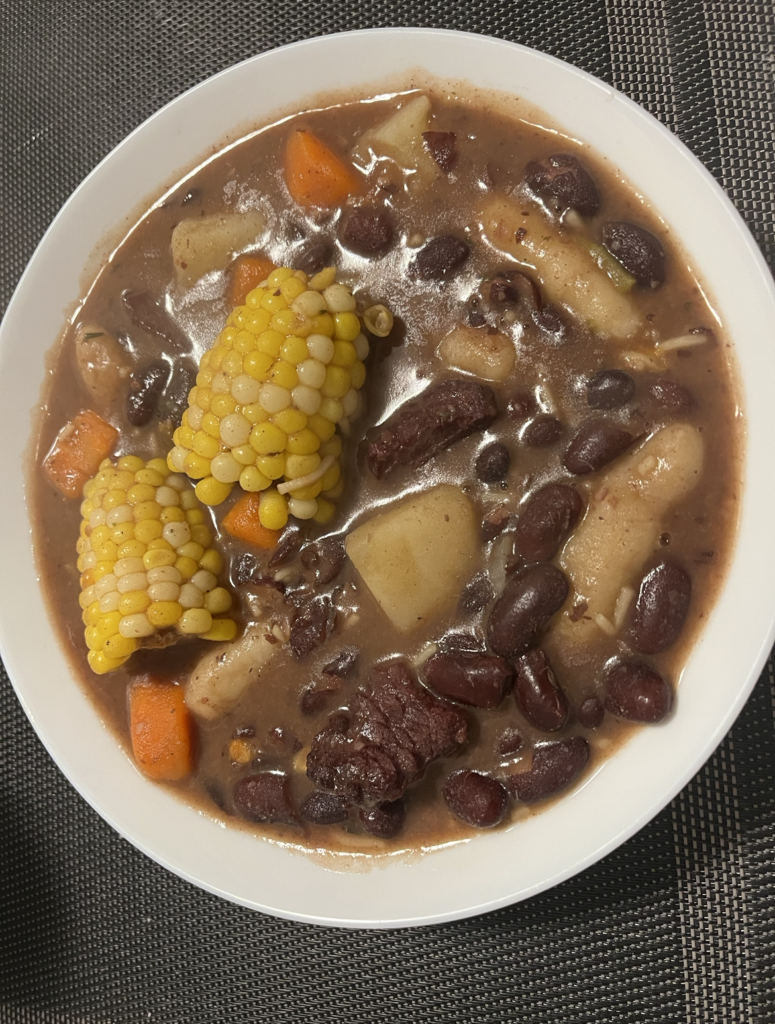 A small bowl of Jamaican red peas soup, made with carrots, salt beef, dumplings, corn and potato. 