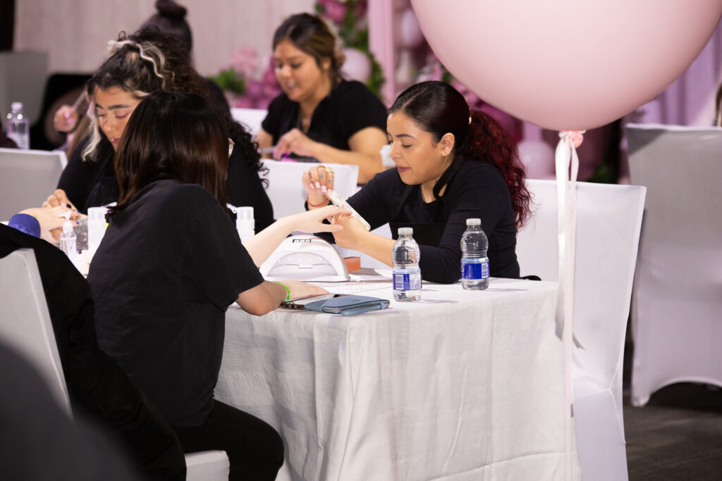 A picture of a nail esthetician doing a manicure for a student. (Hype Hall)