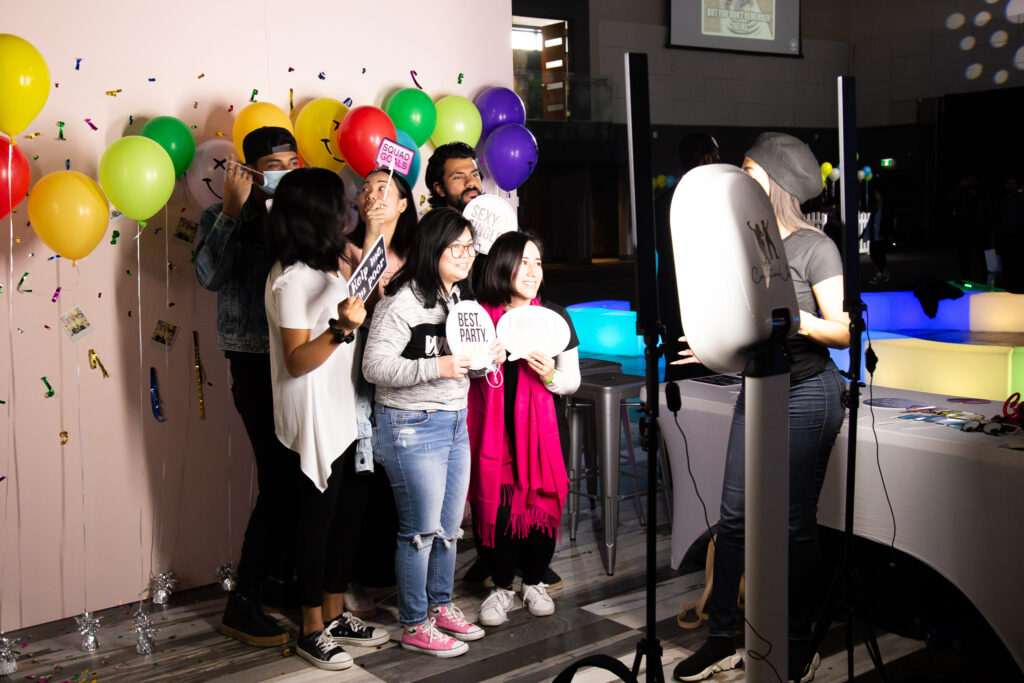 A picture of a group of friends taking pictures at the photo booth.
