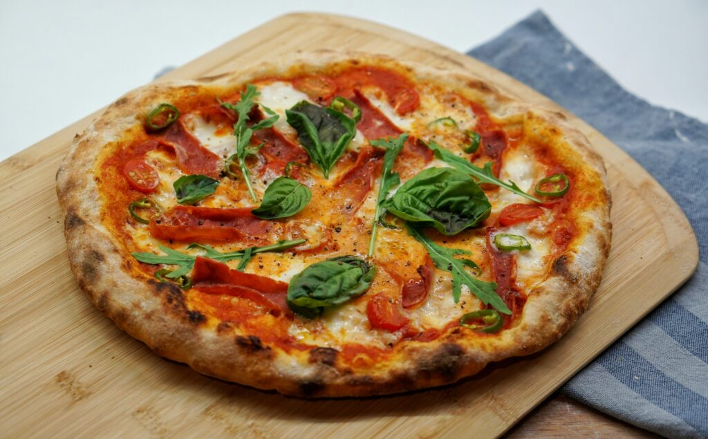 A freshly baked tomato and basil pizza is on a cutting board. 