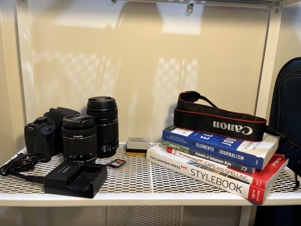 Picture of a DSLR camera and books organized in a shelf.