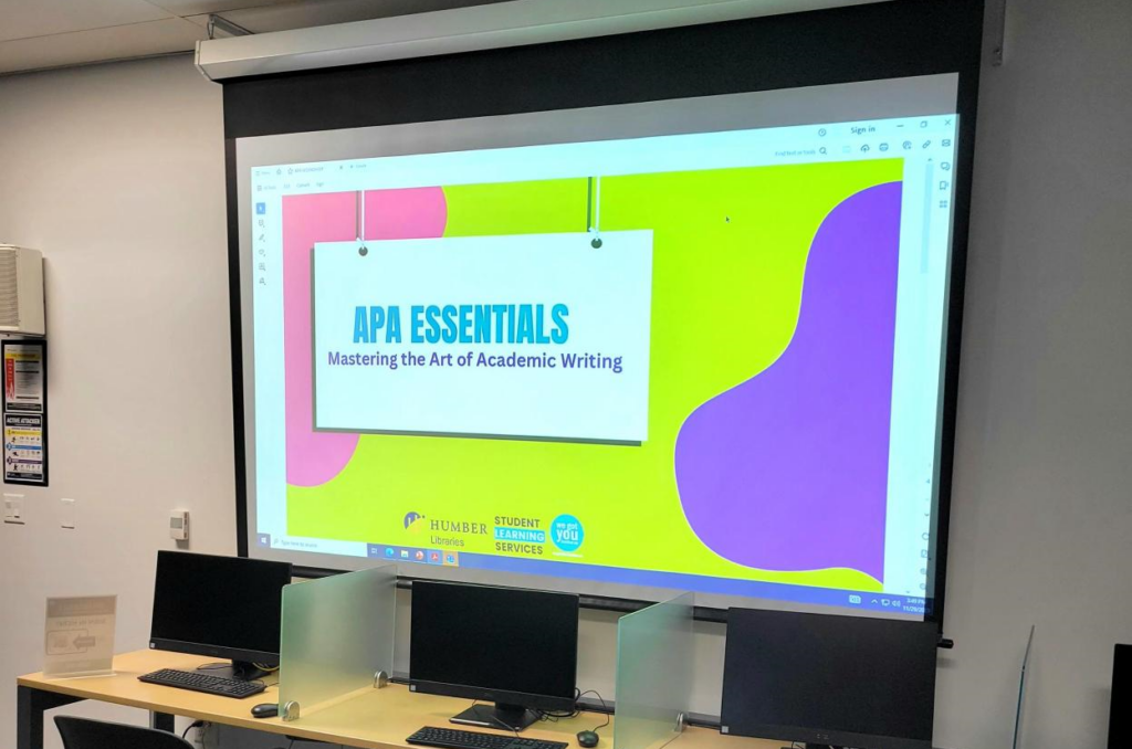A projector displaying the sign "APA Essentials."