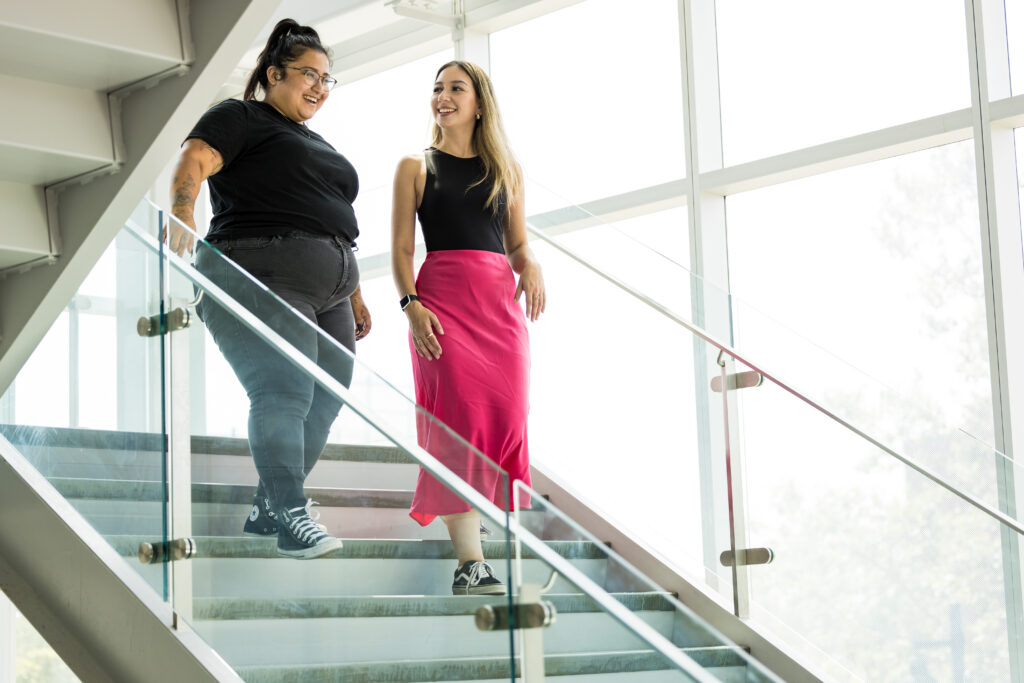Picture of IGNITE Student Advocates Melany Palacios-Naranjo and Jessica Carrera walking down the stairs and talking.