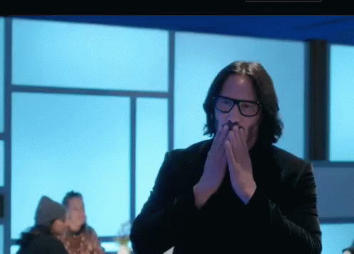 An image of actor Keanu Reeves blowing a kiss at the audience.