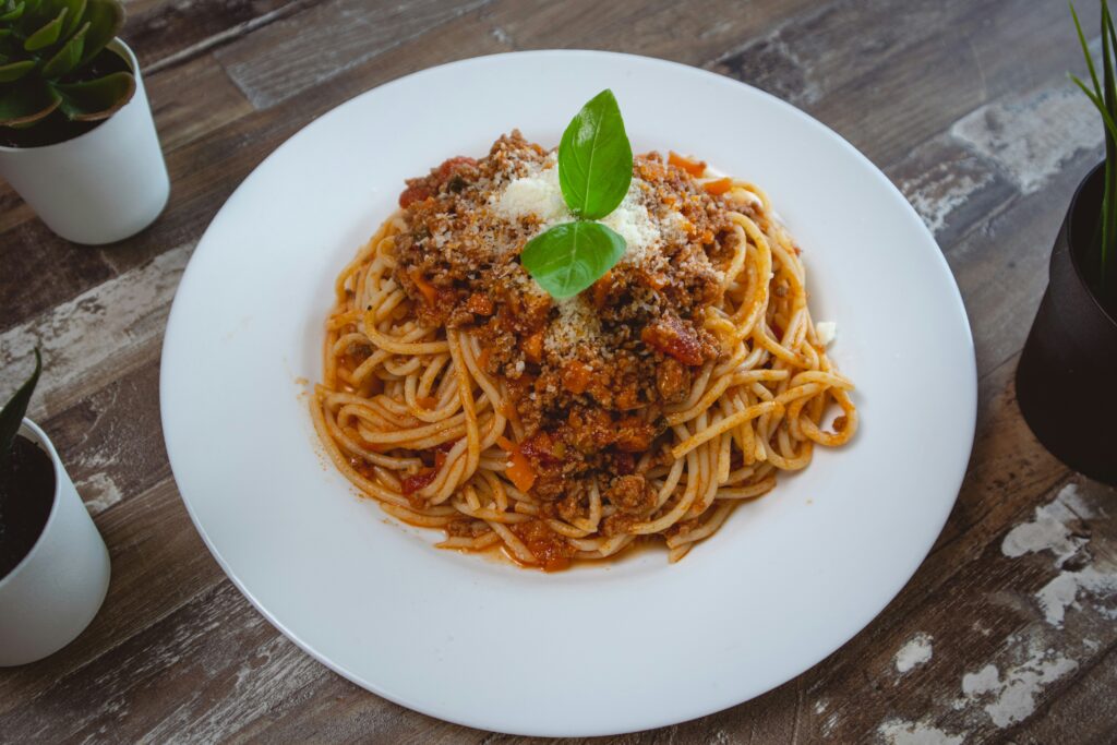 A bowl of homemade spaghetti made with ground beef. The dish is garnished with mint.