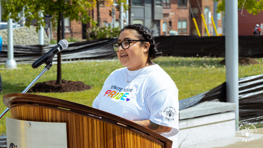 IGNITE Student Advocate Jessica speaking at a lectern at a Pride event.