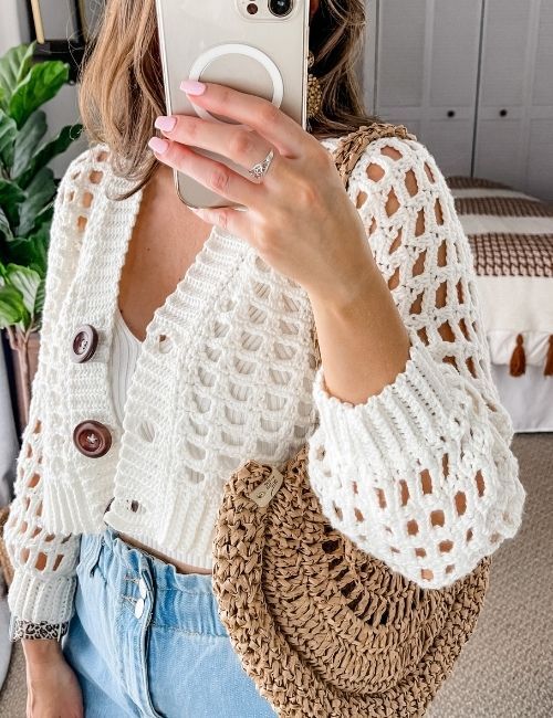 A girl is wearing a trendy crochet cardigan. She pairs it with her favourite rattan bag. (fashion forecast)
