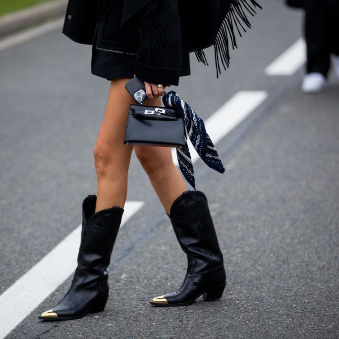 A model is striking a pose in her cowboy boots. She is also holding her phone and favourite purse. (fashion forecast)