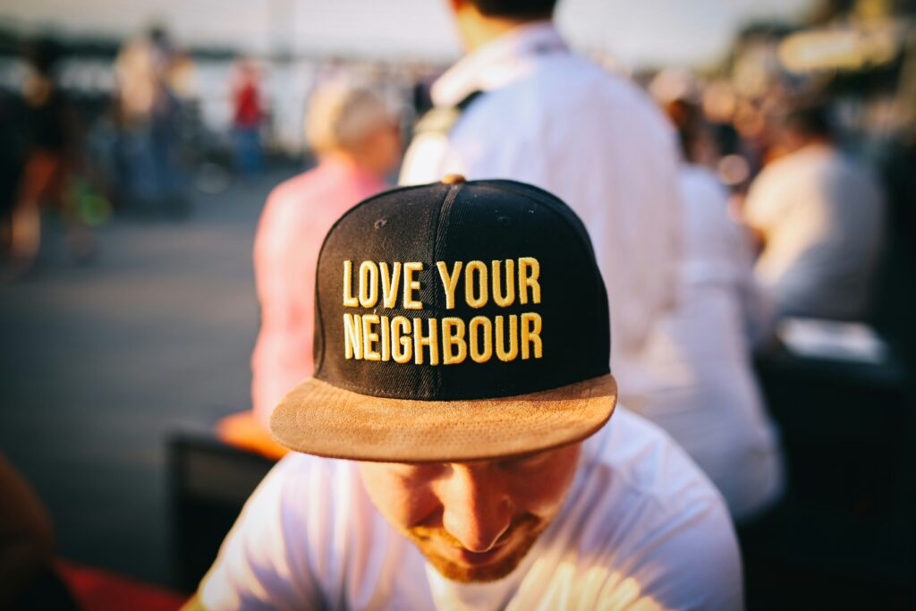 Picture of a man with a hat that writes "love your neighbour."