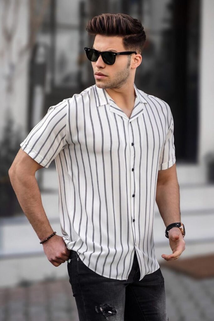 A guy is wearing a black and white striped shirt with shorts.
