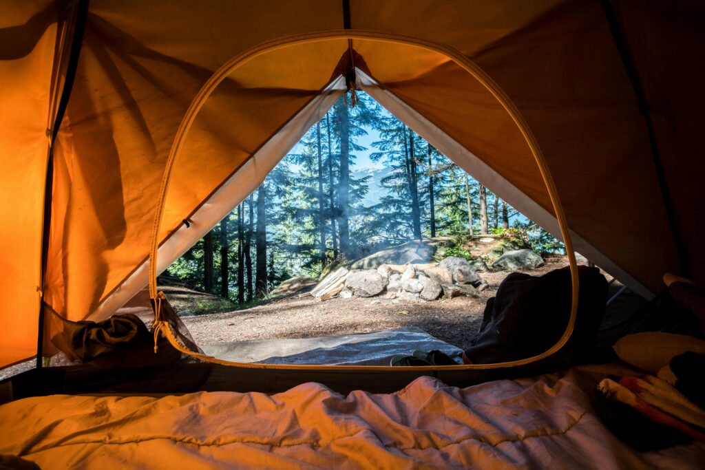 Picture of a camping site taken from inside a tent with a view of trees and rocks.