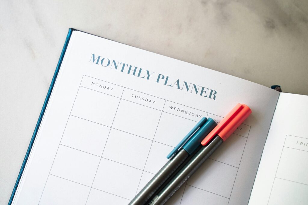 Picture of a monthly planner with two pens sitting on top of it.