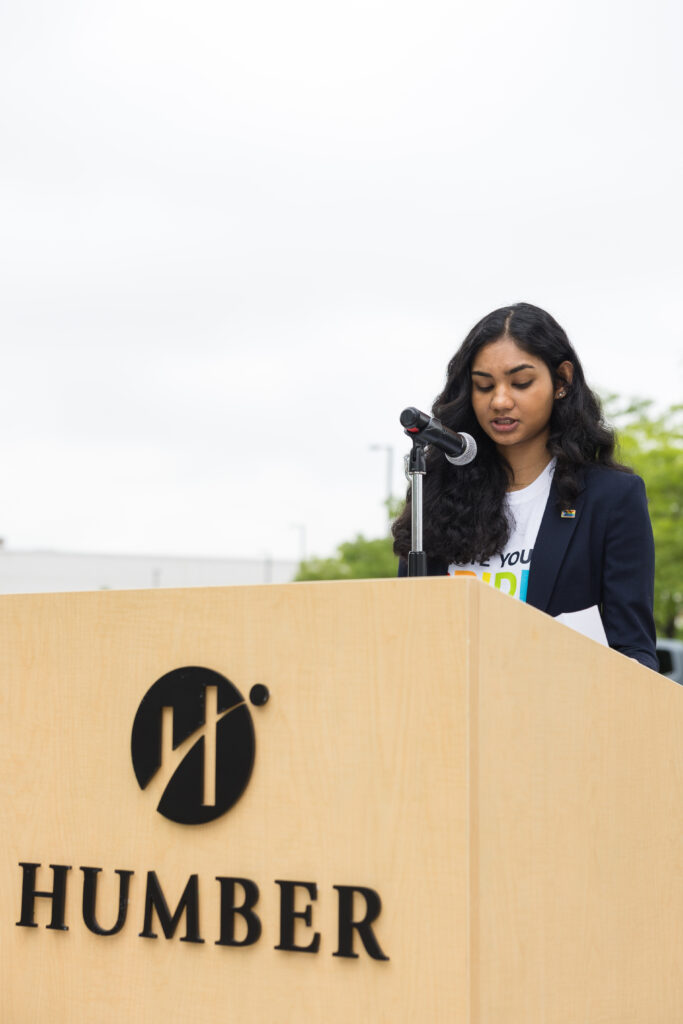 Picture of Student Advocate, Naisha Suthaharan giving a speech on the Pride Flag Raising event at the North campus.
