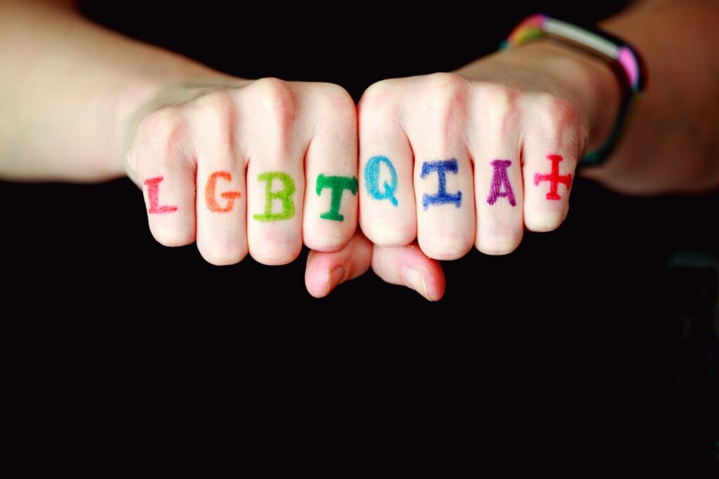 Picture of the word “LGBTQIA+” written on someone’s fingers.