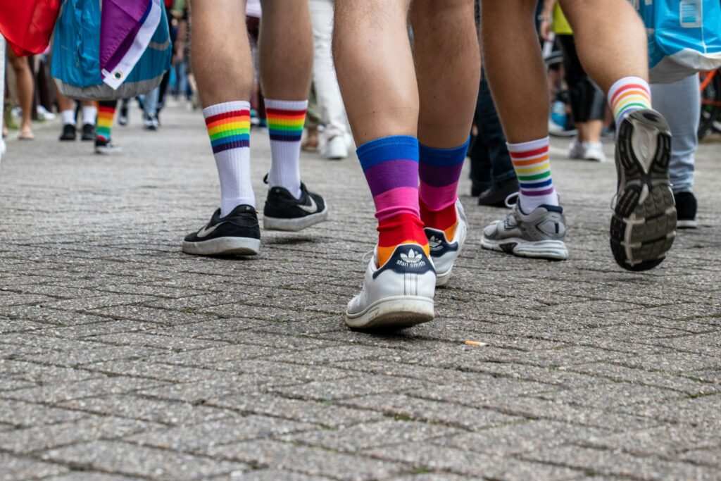 Picture of people walking in the streets wearing pride flag socks.