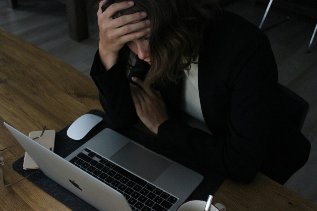 Picture of a woman in a black blazer disappointed looking at her laptop.
