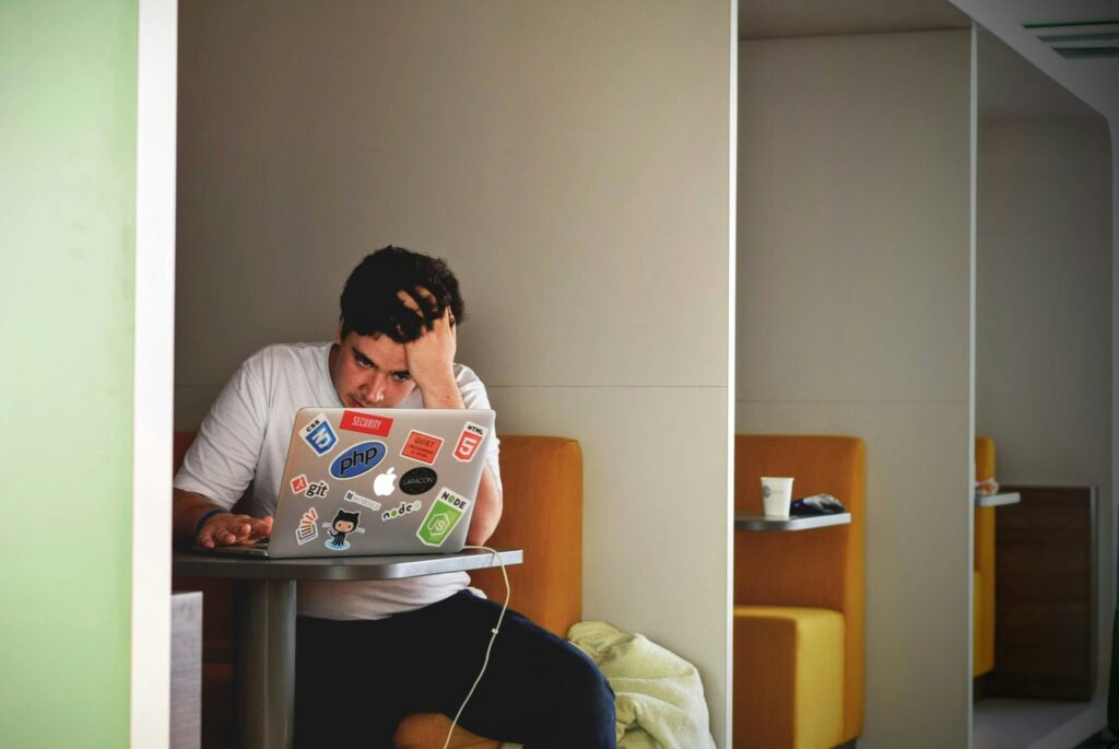Picture of a stressed man using a MacBook.