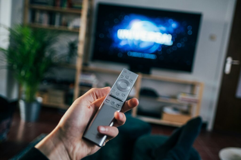 A person holding a remote while watching a movie.