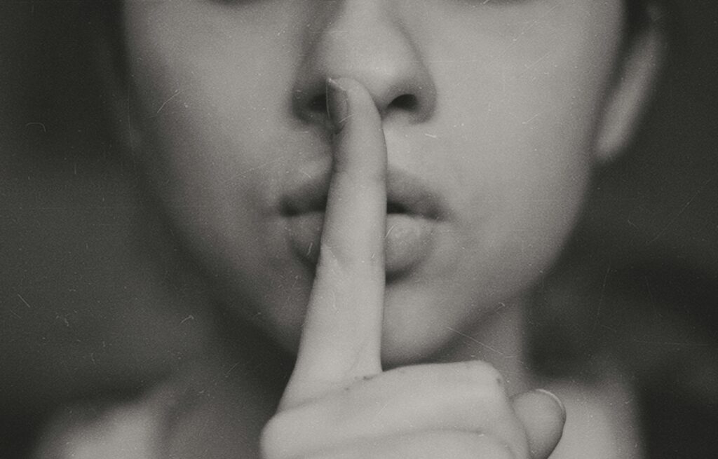 A grayscale photo of a woman doing silent-hand sign.