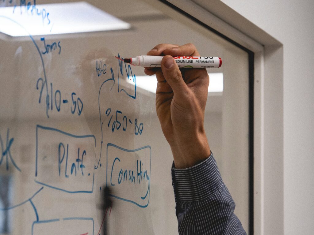 A person writing on a glass with a red marker.